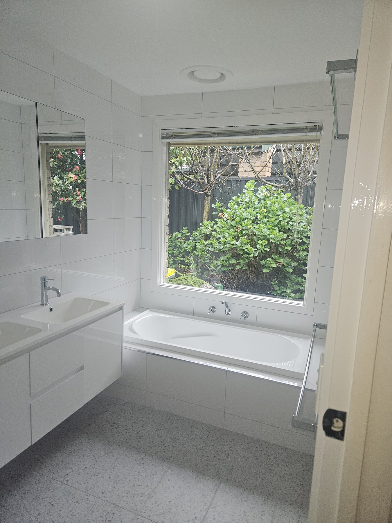 A freestanding bath, tiled walls and a timber-toned vanity.