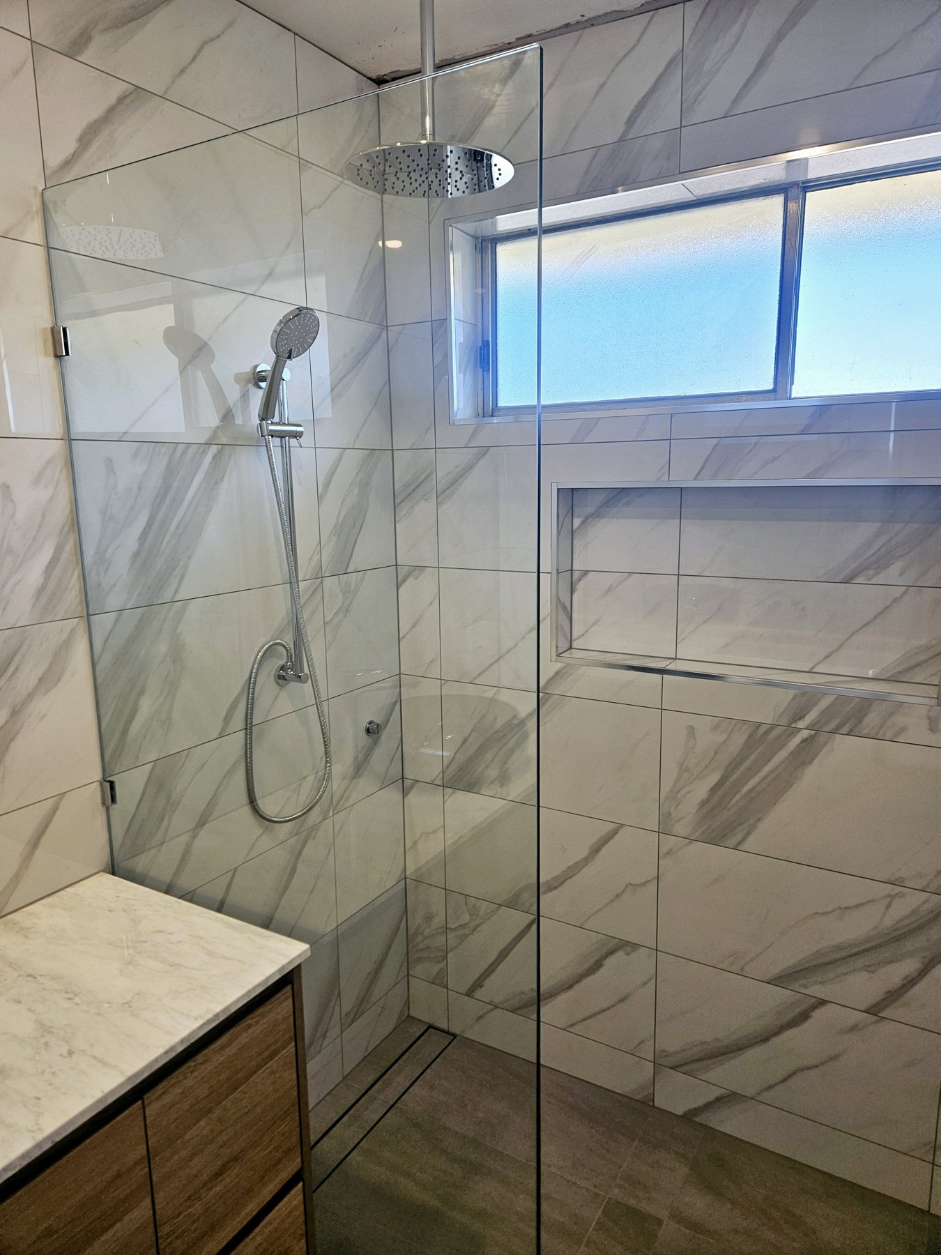 Tiled bathroom with glass shower screen and timber vanity